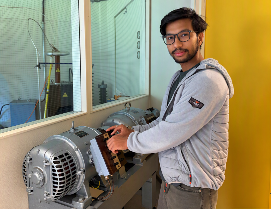 Man with glasses and dark hair working on an engine inside a laboratory